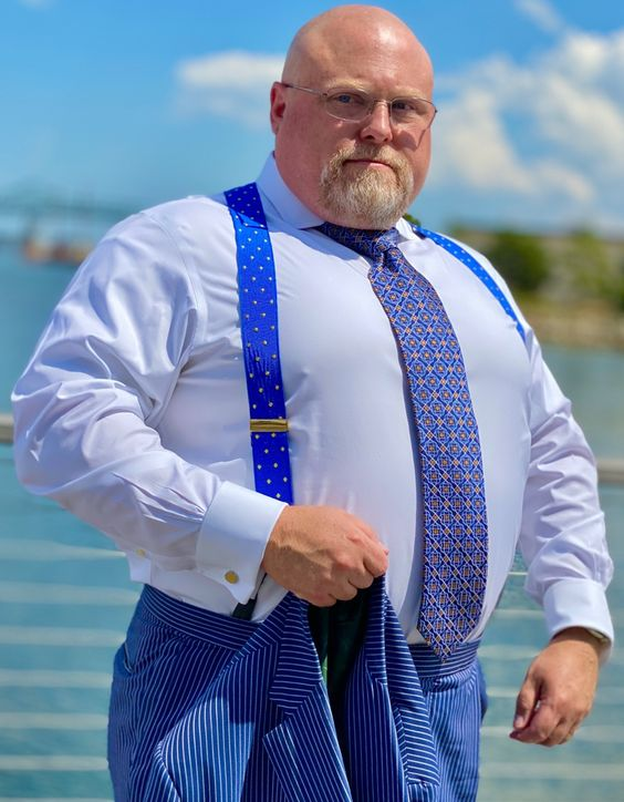 Fat man wearing blue color suspenders which we is reviewed as one of the best suspenders for fat guys/men